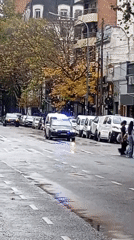 Police vehicle with flashing lights observed on wet Buenos Aires street