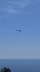 Paramotorist flies over calm seas near Calella, Spain