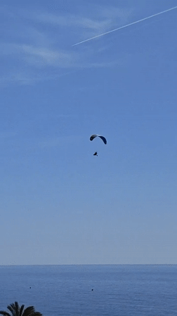 Paramotorist flies over calm seas near Calella, Spain
