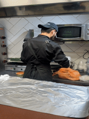 Cook prepares food in Bugry kitchen amid nighttime cityscape