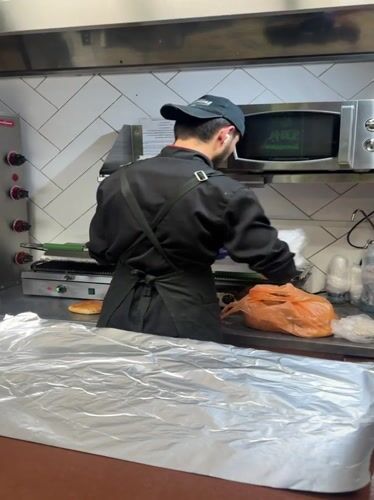 Cook prepares food in Bugry kitchen amid nighttime cityscape
