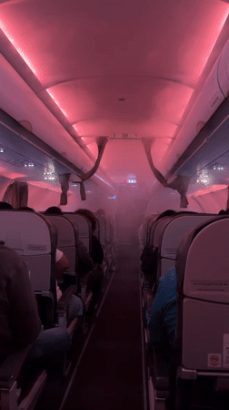 Pink-lit airplane cabin aisle, first-person view near New Delhi