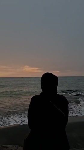 Solitary figure contemplates ocean at dusk in Lhokseumawe