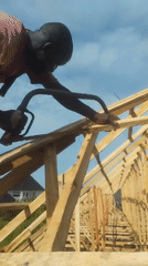 Construction worker builds wooden roof framework in Agbarha-Otor