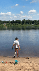 Boy stands on sandy shore overlooking water in Yaroslavl