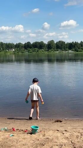 Boy stands on sandy shore overlooking water in Yaroslavl