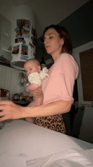Mother drinks water while holding baby in Moscow kitchen