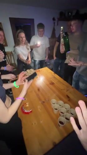 Young adults play beer pong at night party in Dunevo