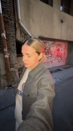 Woman takes selfie while fixing hair in Tbilisi alleyway