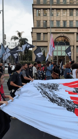 Protesters march through São Paulo streets with banners, signs