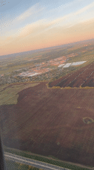 Aerial sunset view captures patchwork farmland from aircraft window