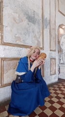 Costumed woman poses with bread in Moscow indoor setting