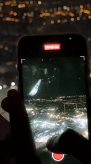 Passenger films nighttime flight showing wing and city lights below