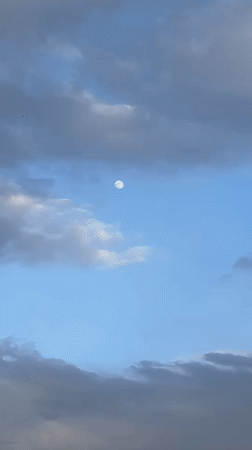 Daytime moon visible through clouds over Hudson