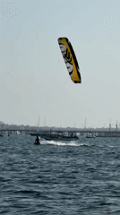 Kitesurfers ride Bali's coast alongside a moored outrigger boat