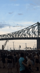 Festival crowd gathers under stormy skies near Jacques Cartier Bridge