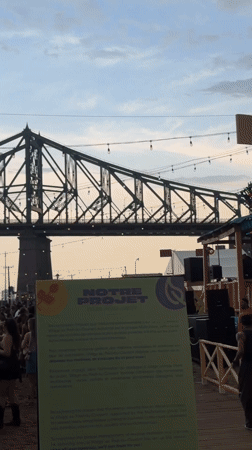 Festival crowd gathers under stormy skies near Jacques Cartier Bridge