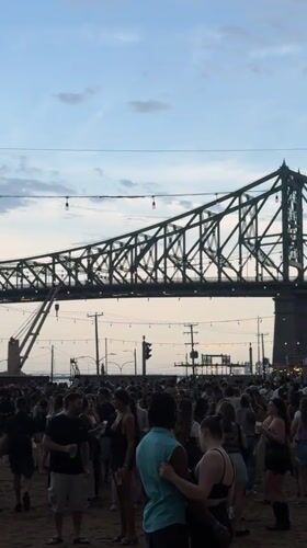 Festival crowd gathers under stormy skies near Jacques Cartier Bridge