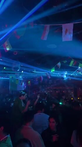 Packed indoor venue with international flags and low lighting