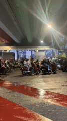 Motorcyclists shelter under Jakarta bridge during evening rainfall