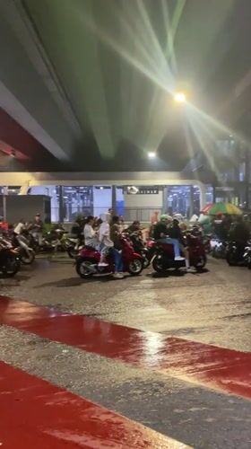 Motorcyclists shelter under Jakarta bridge during evening rainfall