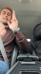Young man makes hand gestures in car driver's seat