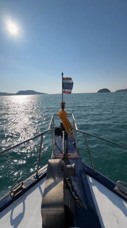 Boat travels through calm waters near Rawai, Thailand