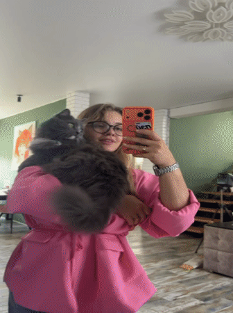 Woman takes mirror selfies with gray cat in Russian home