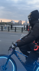 Cyclist crosses London bridge at dusk wearing dark clothing