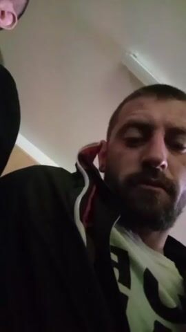 The video shows a room with several men sitting down, most of them wearing yellow safety vests. Some appear to be listening, while others are looking around. The person recording the video moves the camera around to show the other individuals in the room.