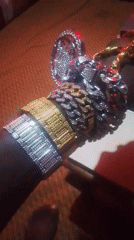 Person displays Nigerian currency while wearing elaborate jewelry indoors