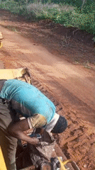 Construction worker maintains heavy machinery on Nigeria dirt road