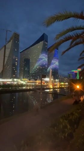 Evening lights illuminate modern Batumi cityscape and recreation areas
