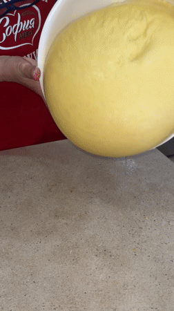 Baker pours yellow dough in Bulgarian kitchen