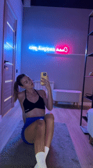 Woman Takes Mirror Selfies in Neon-Lit Fitness Studio