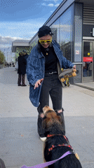 Woman with skateboard greets dog outside Moscow building