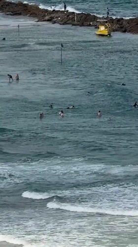 Surfers, sailboats, and aircraft over the Netanya coast