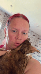 Woman cuddles brown tabby cat on dinosaur-printed bedding