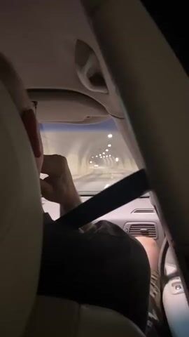 The video shows the interior of a car driving through a tunnel at night. The camera is positioned behind the passengers, looking forward. The tunnel is illuminated by a series of lights. The passenger in the foreground is wearing a seatbelt and has their arm raised to their face. The audio is in Russian and discusses the car's speed and the location, mentioning Norway. There is no visible text in the video.
