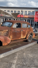 Vintage rusted sedan displayed in Cologne cobblestone square