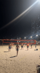 Nighttime beach volleyball and street activity in coastal city