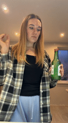 Woman examines green bottle in Dreiliņi, Latvia