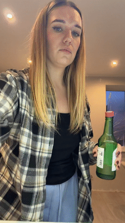 Woman examines green bottle in Dreiliņi, Latvia