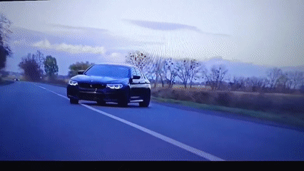 Black BMW travels rural road in Nizhnevartovsk under overcast skies