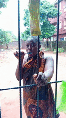 Woman brushes teeth behind fence in Nkpor, Nigeria