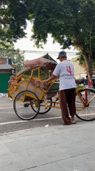 Community gathering with pink-shirted groups and pedicabs in Purwodadi