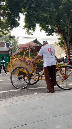 Community gathering with pink-shirted groups and pedicabs in Purwodadi