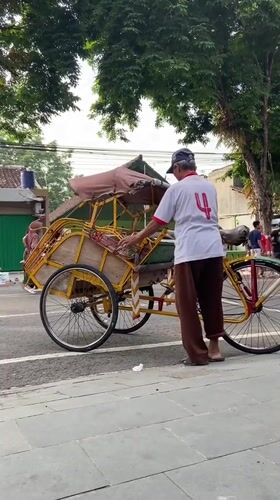 Community gathering with pink-shirted groups and pedicabs in Purwodadi