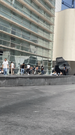 Skateboarder performs tricks in Barcelona plaza during sunny afternoon
