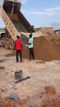 Construction workers oversee sand delivery in Angwan Sayawa, Nigeria